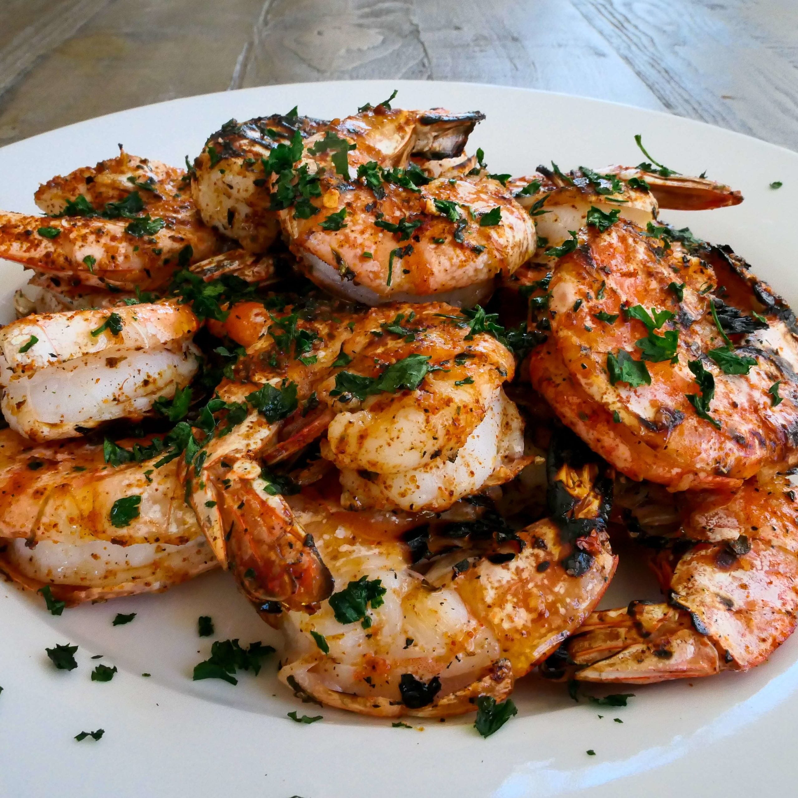 cajun grilled shrimp on white plate garnished with fresh parsley