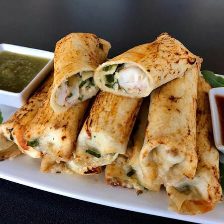 baked shrimp taquitos served on a white plate with salsa