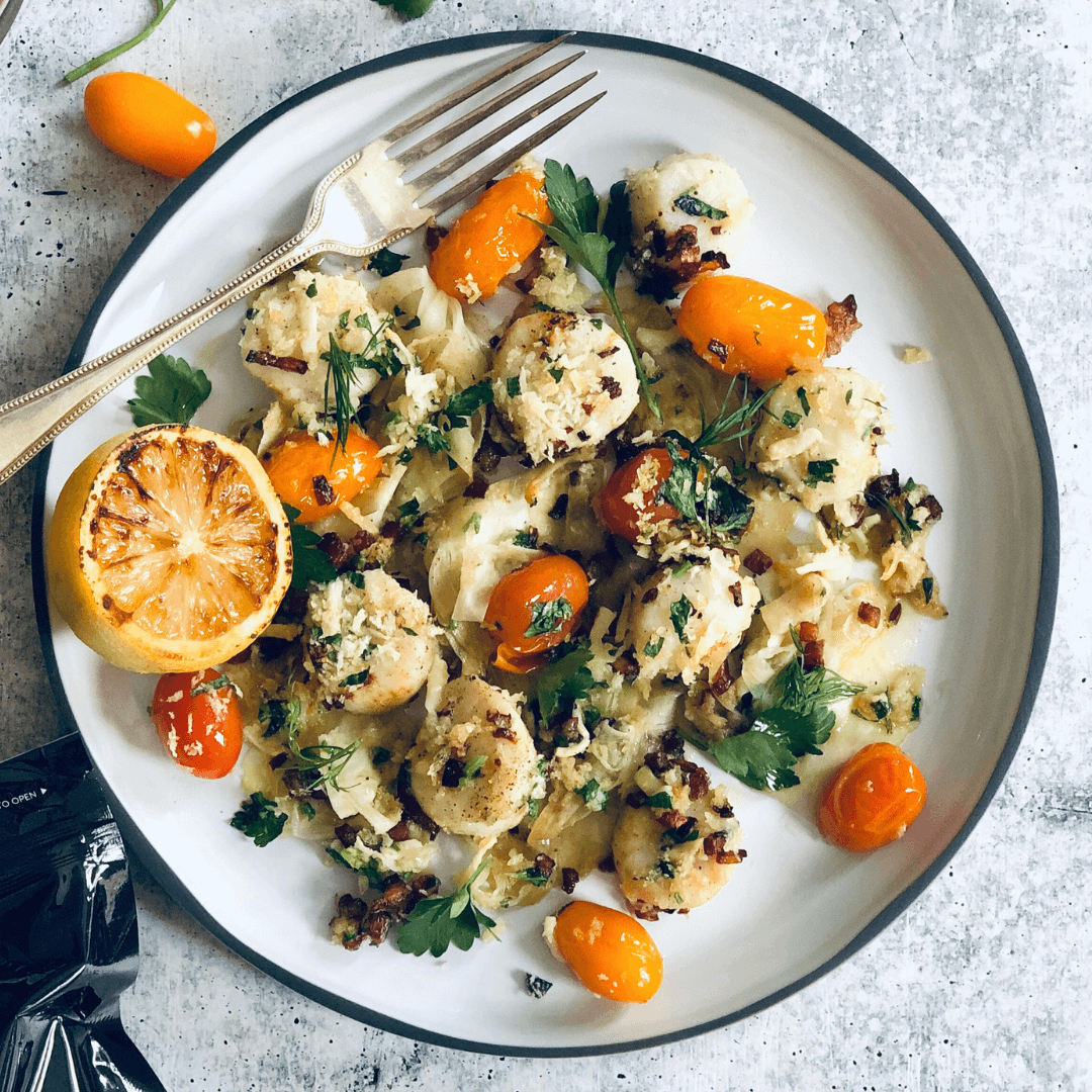 brown butter scallops with cherry tomatoes served on a white plate