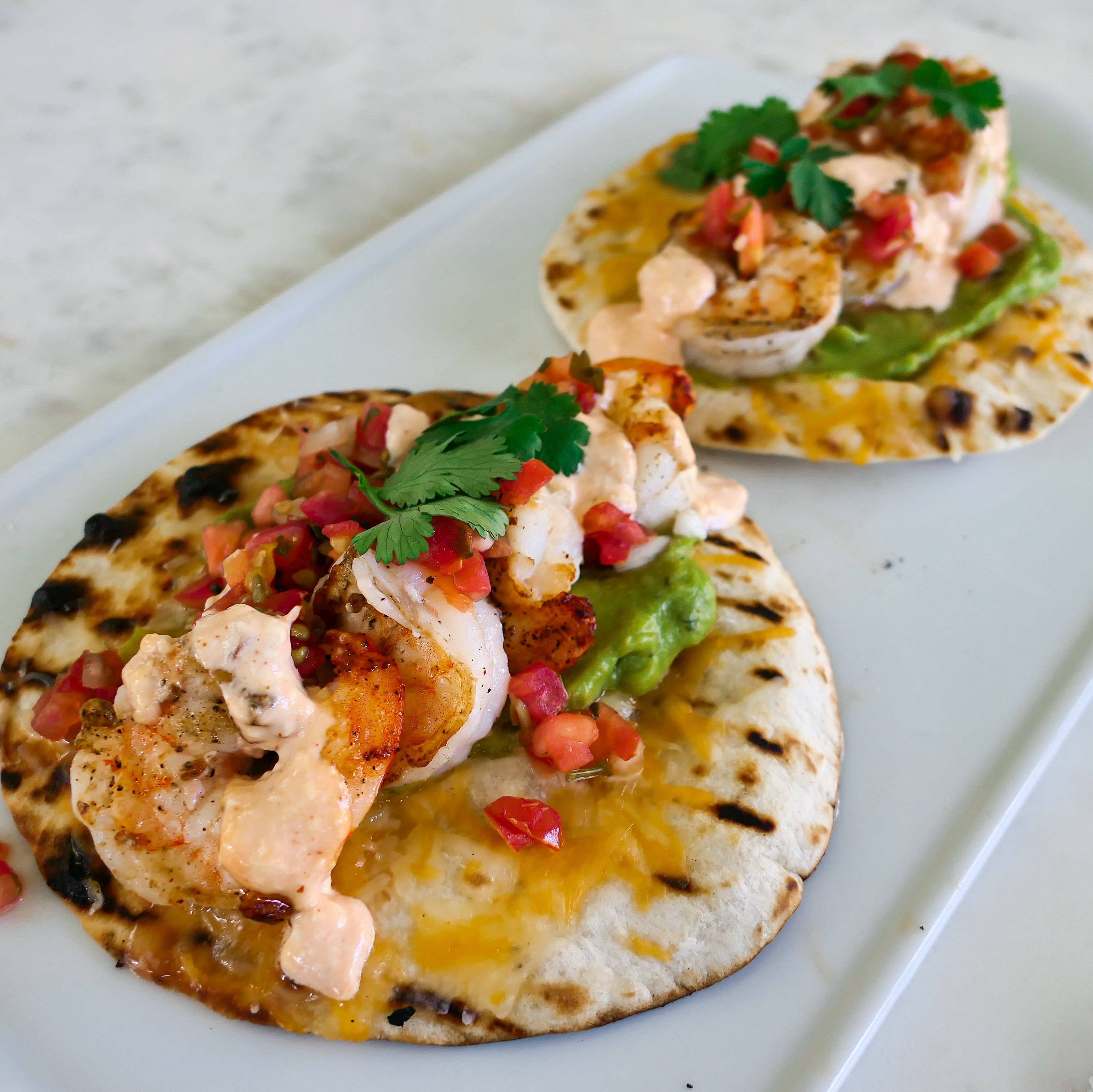 grilled shrimp tacos topped with chipotle aioli and cilantro leaves