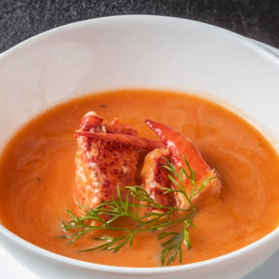 A bowl of lobster bisque with claw meat garnish.