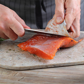 A home chef cleans a salted salmon fillet on a cutting board.