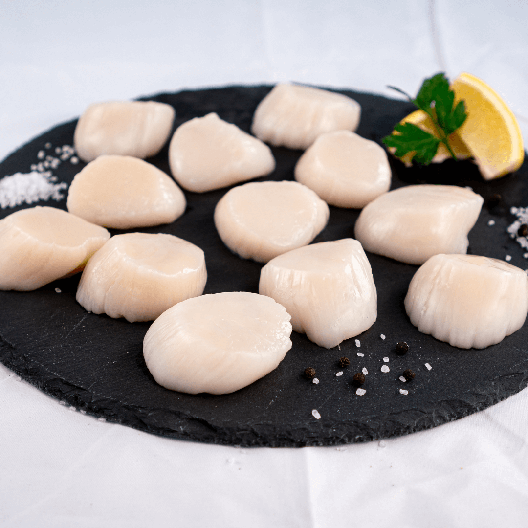 10-20 jumbo sea scallops on a black slate slab with lemon, parsley, and salt crystals