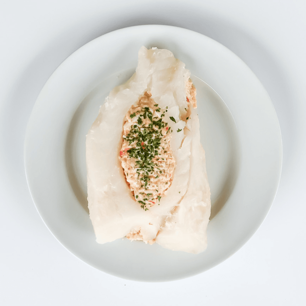crab stuffed cod raw portion on a white plate