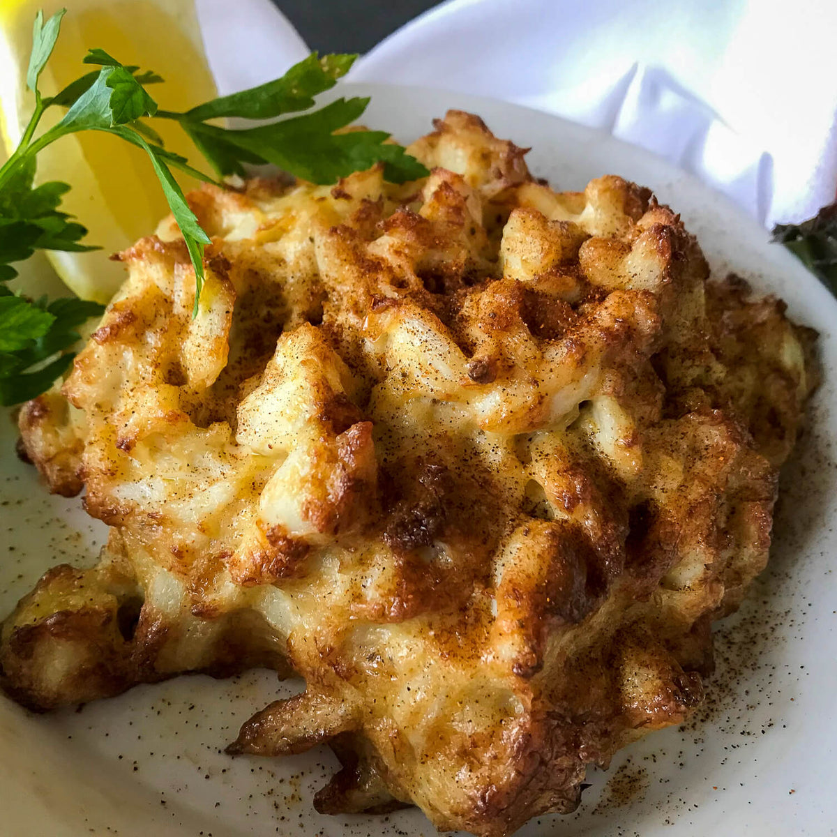 baked crab imperial in a white dish with lemon and parsley on the side