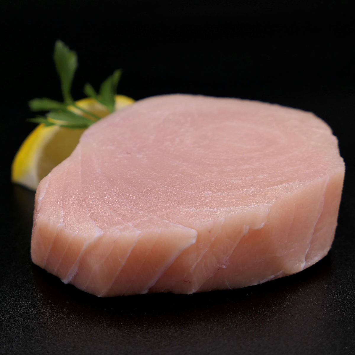 8 ounce fresh swordfish steak with lemon and parsley in background