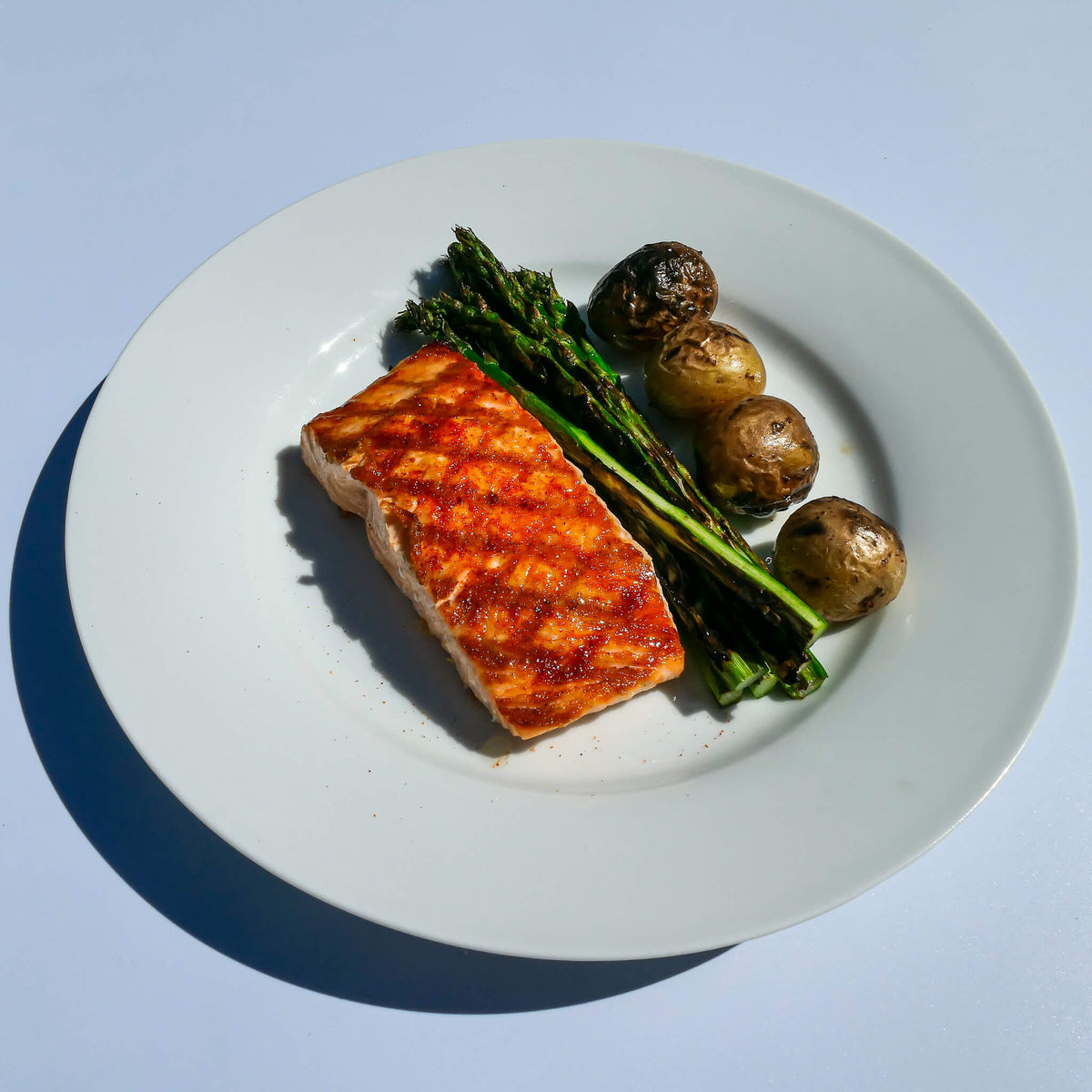 grilled salmon with asparagus and potatoes on a white plate