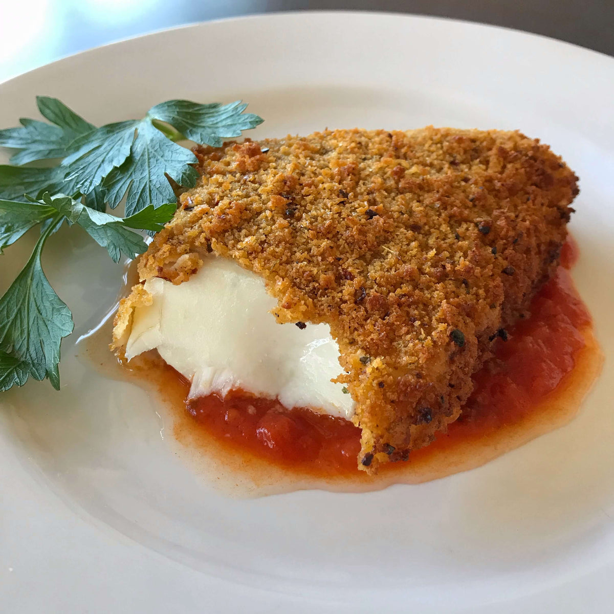 breaded haddock on red sauce served on a white plate 