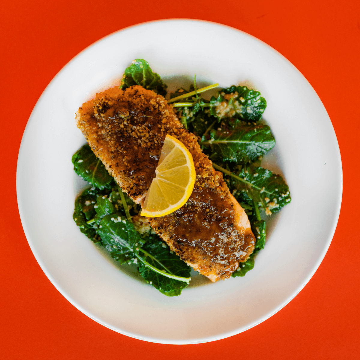 Norwegian salmon baked with honey mustard and served over greens on a white plate