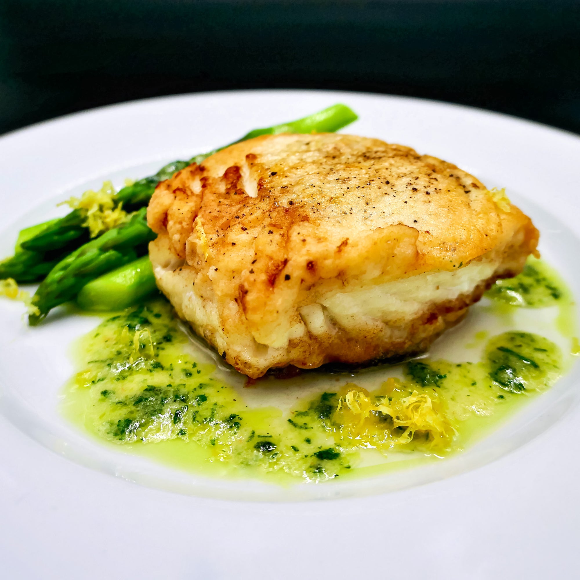 6 ounce portion of fresh halibut with lemon and parsley in the background