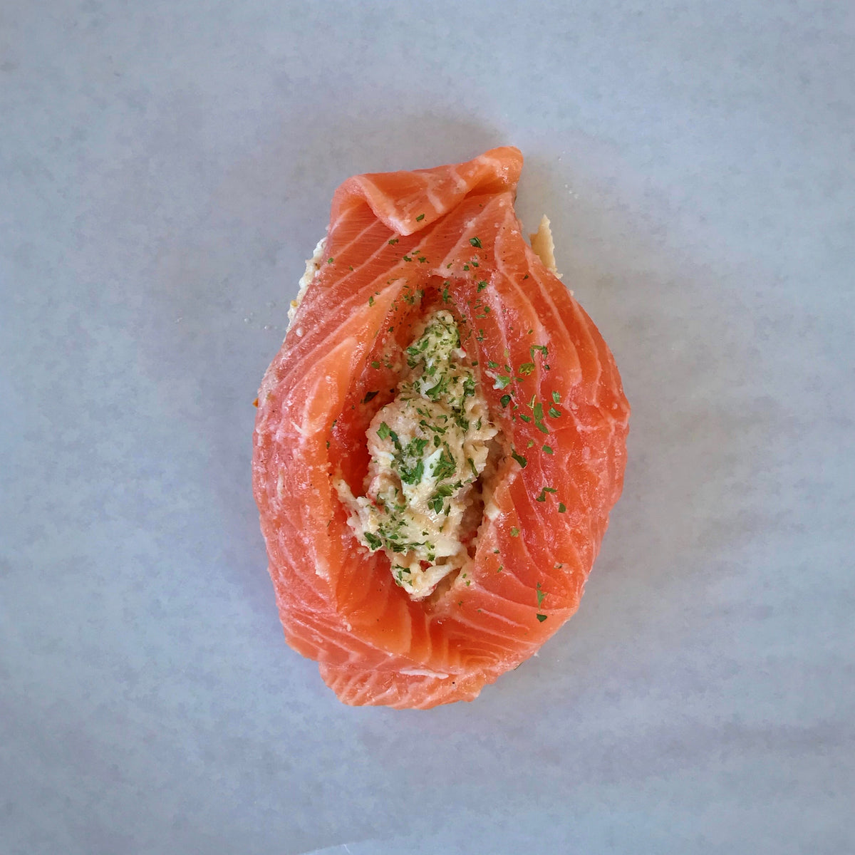 raw stuffed salmon on a sheet of parchment paper