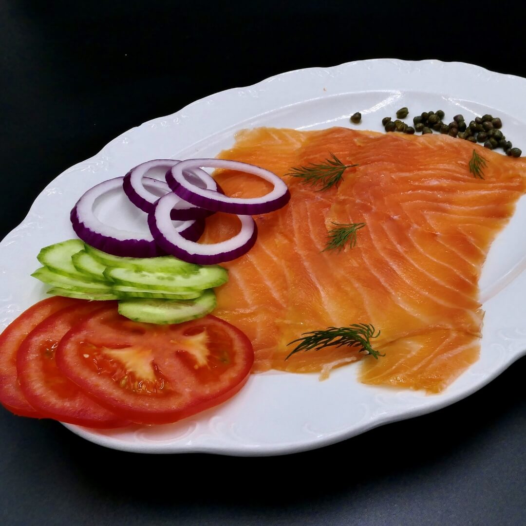 smoked salmon on a plate with tomato cucumbers and red onion