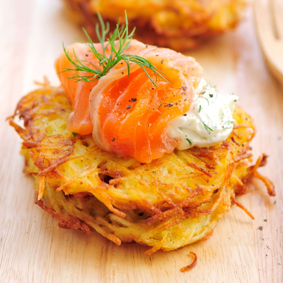 smoked salmon latkes topped with parsley on wooden plate