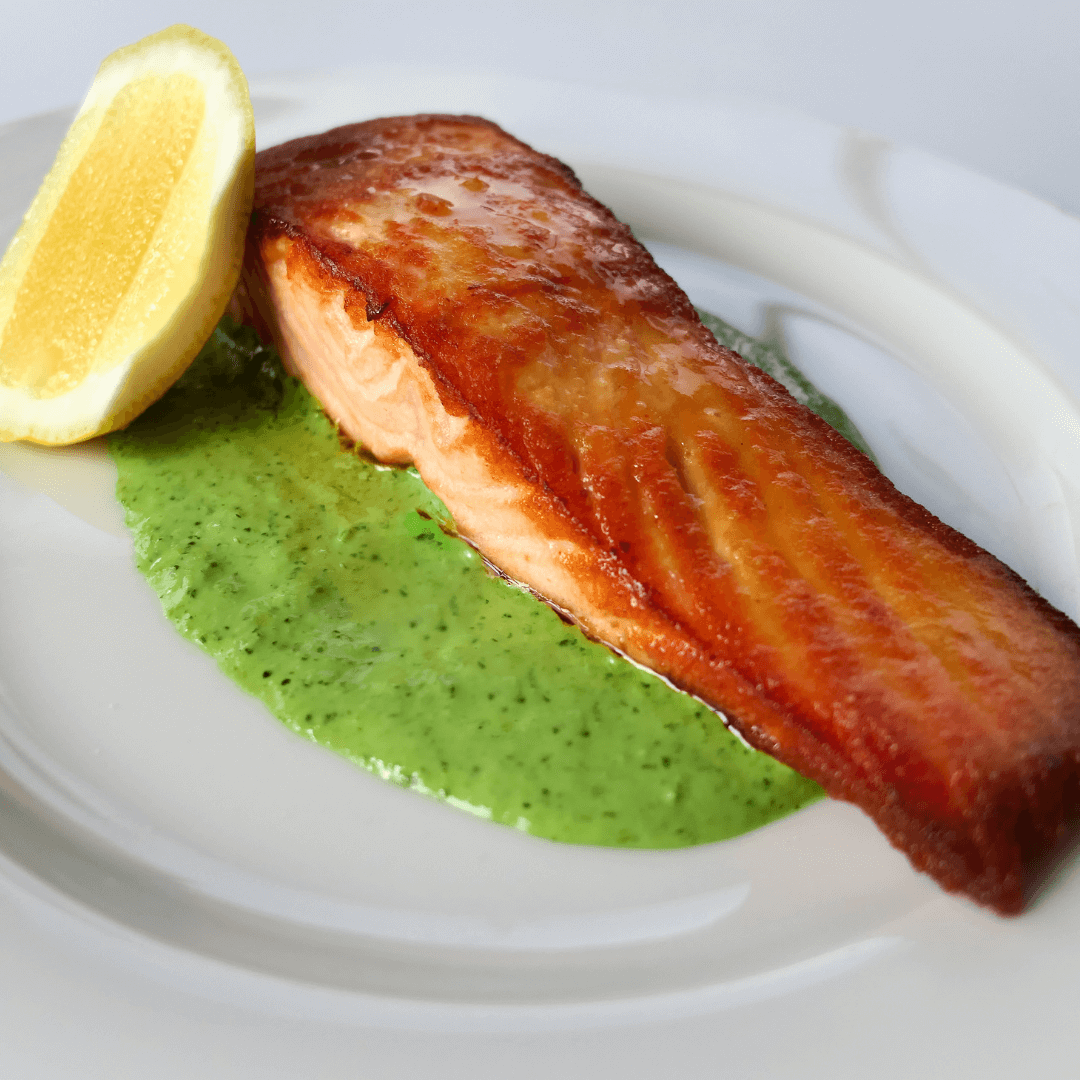 pan seared fresh salmon with a lemon wedge on the side served on a white plate