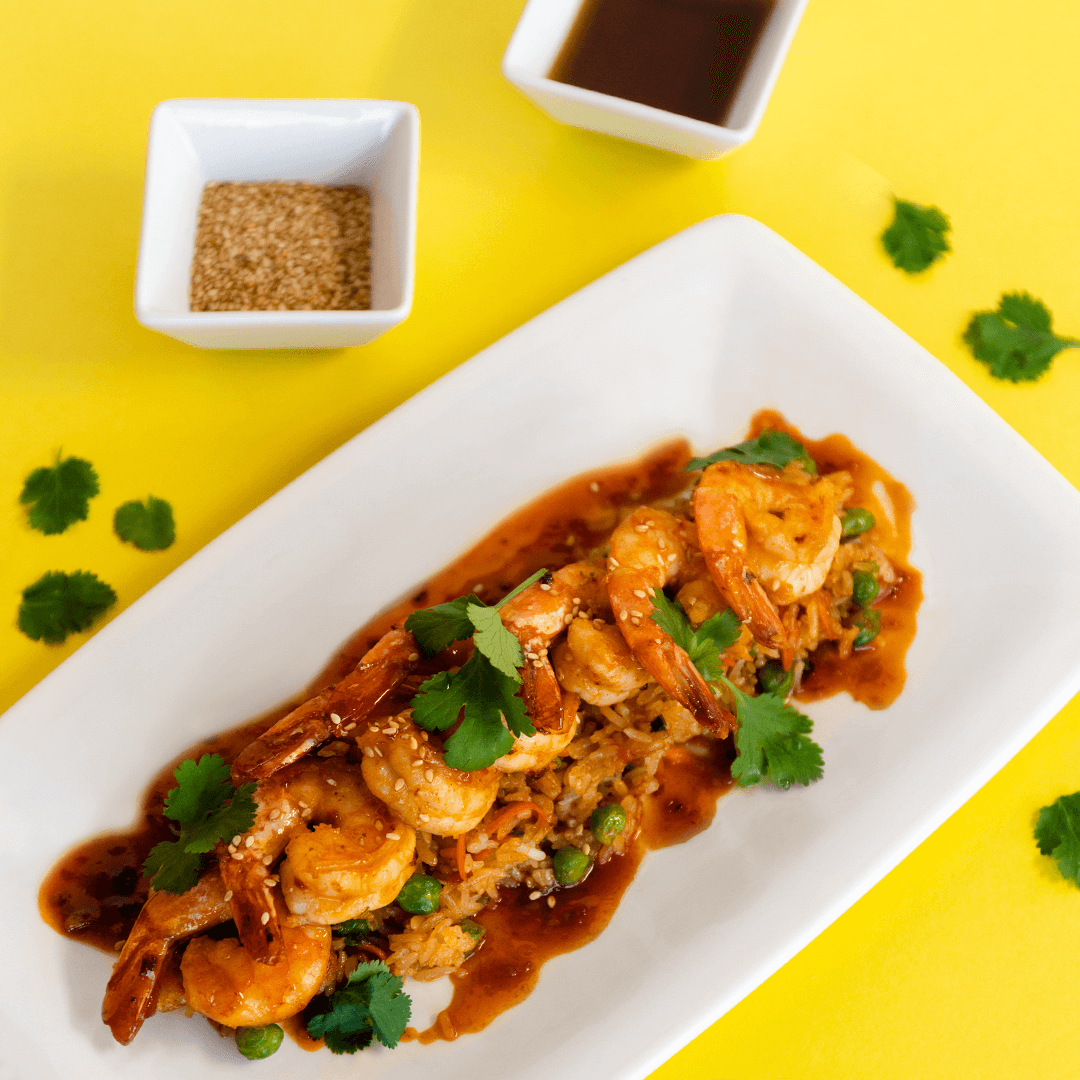 baked shrimp recipe with spicy sauce served over rice on a white plate