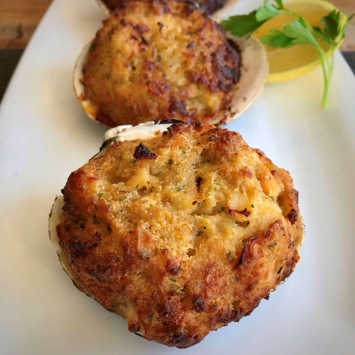 baked stuffed clams on a white plate with lemon and parsley