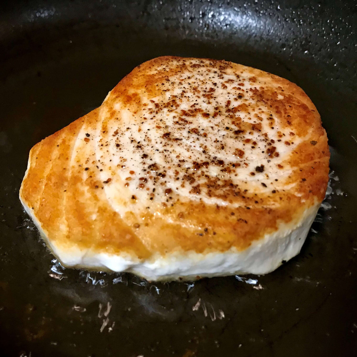 swordfish steak cooking on a pan
